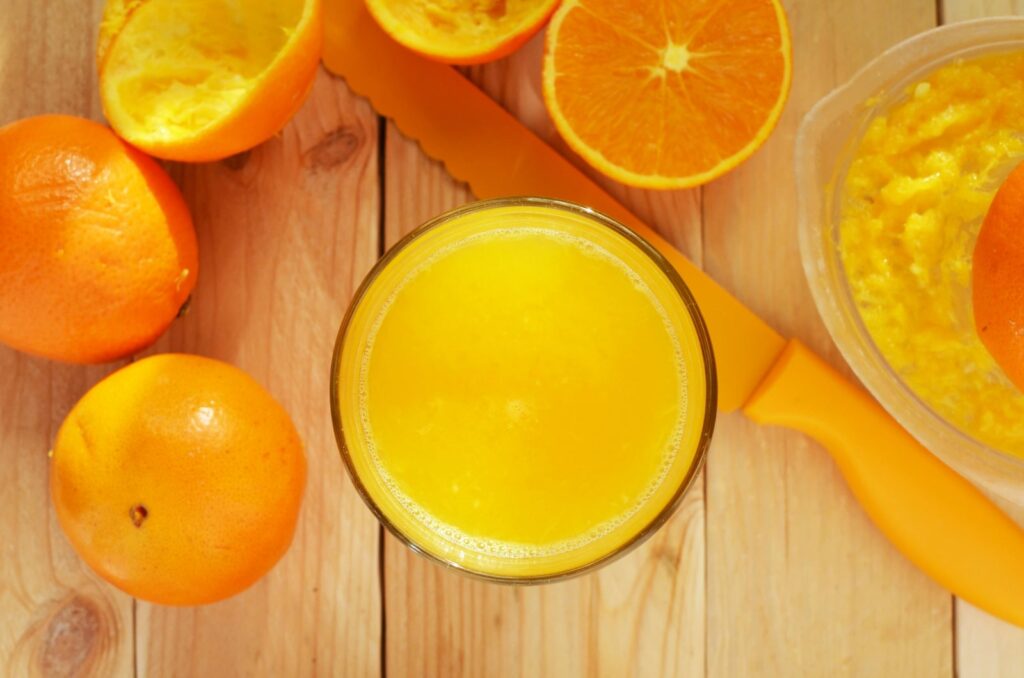 A bowl of fresh orange juice accompanied by a knife, elegantly placed on a wooden table.