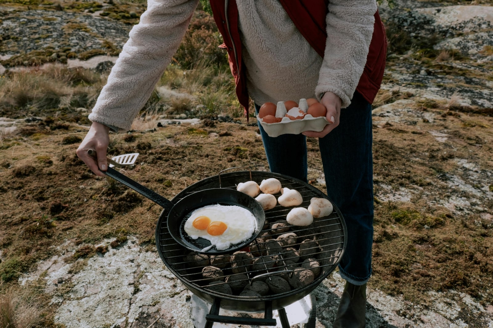 A person skillfully cooking eggs on a grill, showcasing culinary expertise and outdoor cooking techniques.