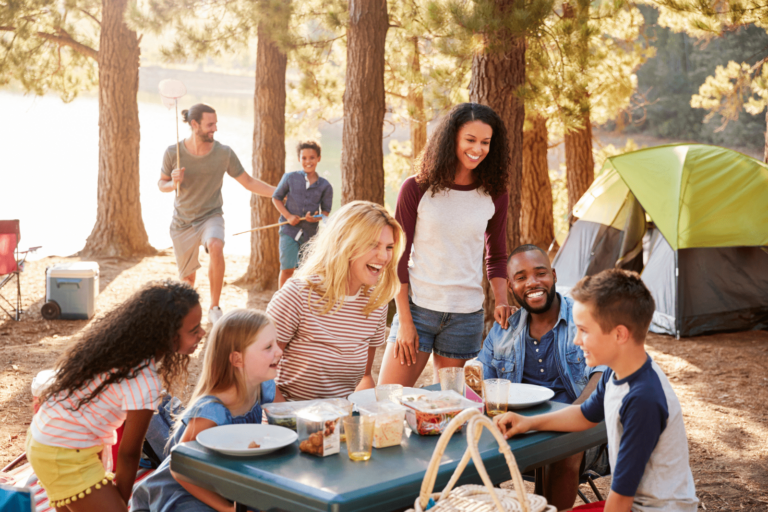 A family enjoys a picnic in a serene wooded area, surrounded by trees and nature's beauty.