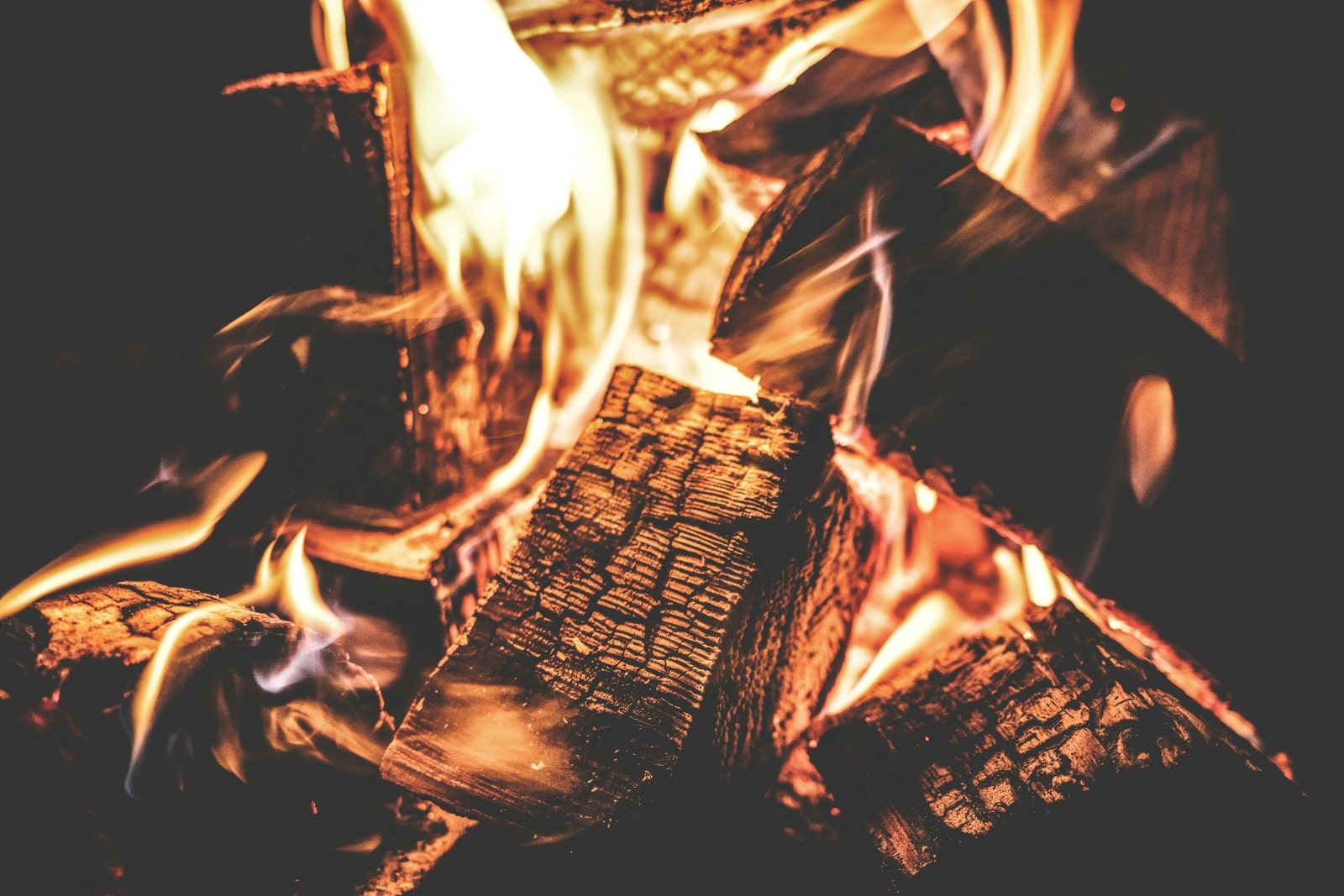 A close-up view of a vibrant fire, showcasing glowing flames and charred logs, creating a warm and inviting atmosphere.