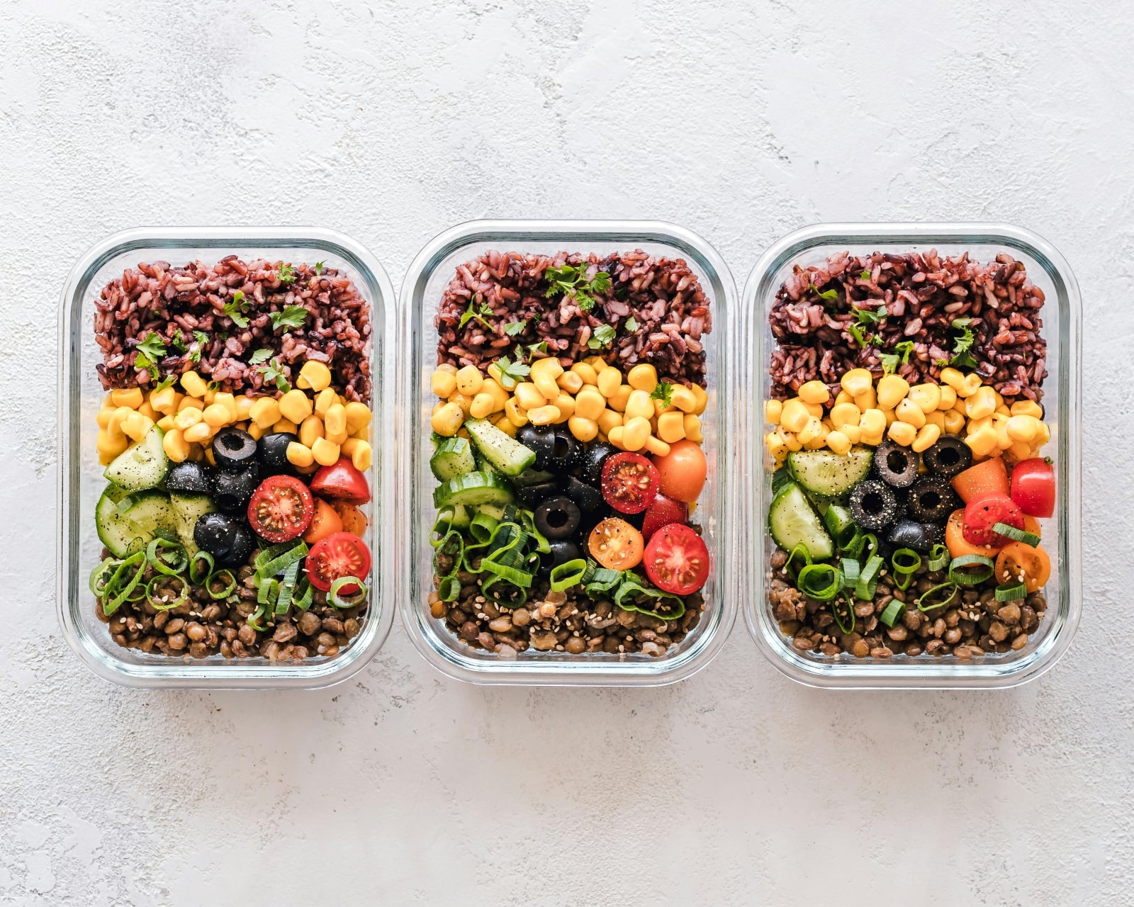 Three containers filled with various types of food, showcasing a colorful assortment of ingredients and dishes.