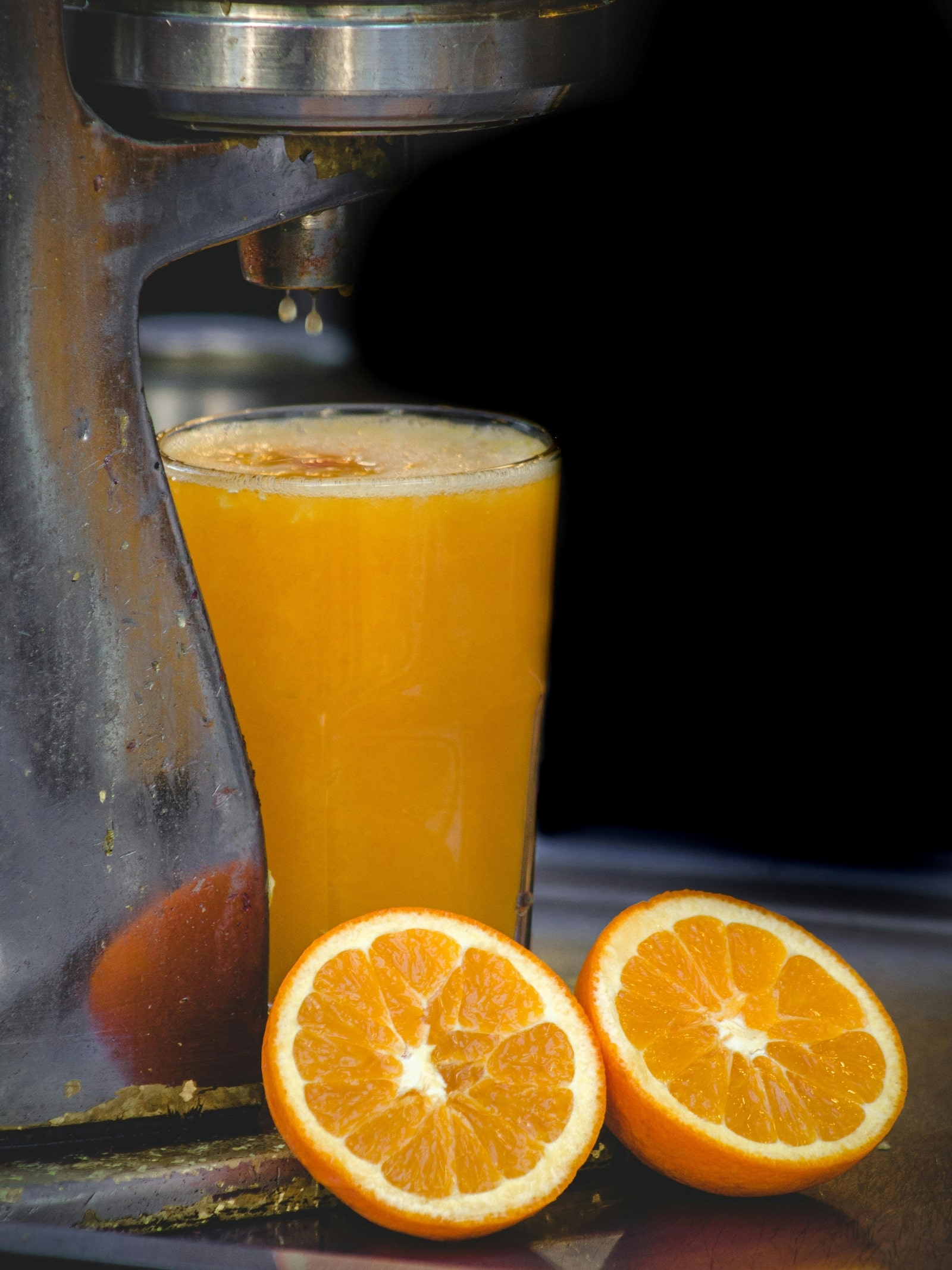 A juice maker beside a glass filled with freshly squeezed orange juice, showcasing vibrant color and refreshing appeal.