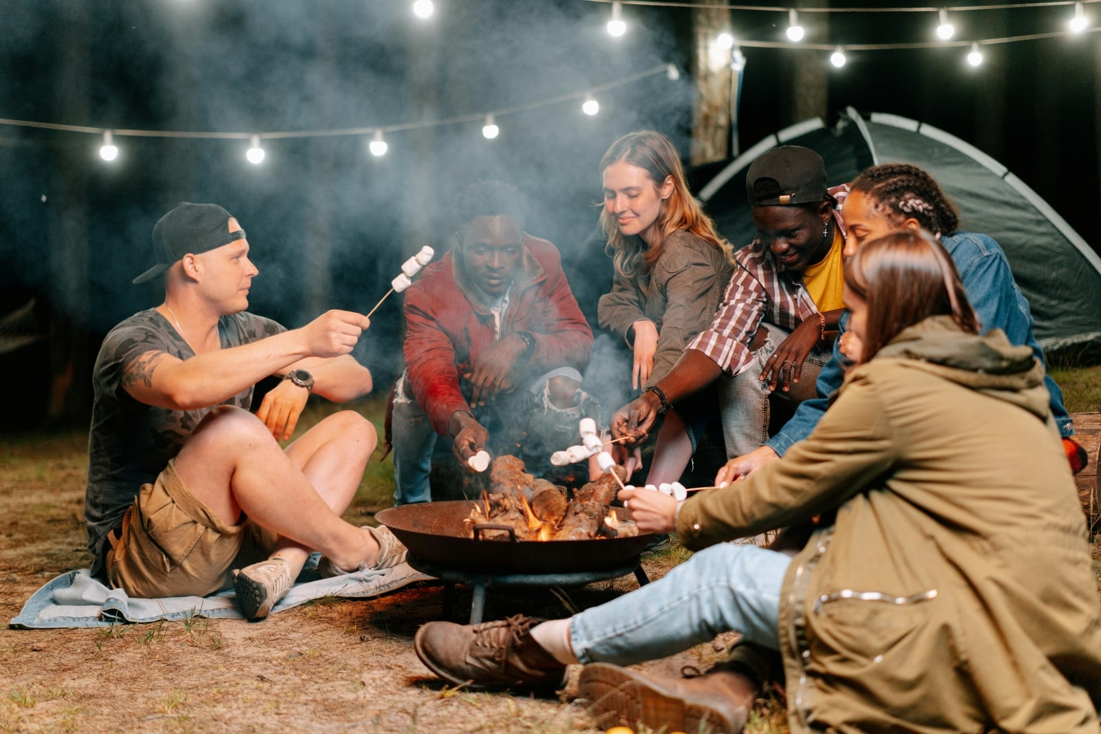 A diverse group of individuals gathered around a warm campfire, sharing stories and enjoying the evening atmosphere.