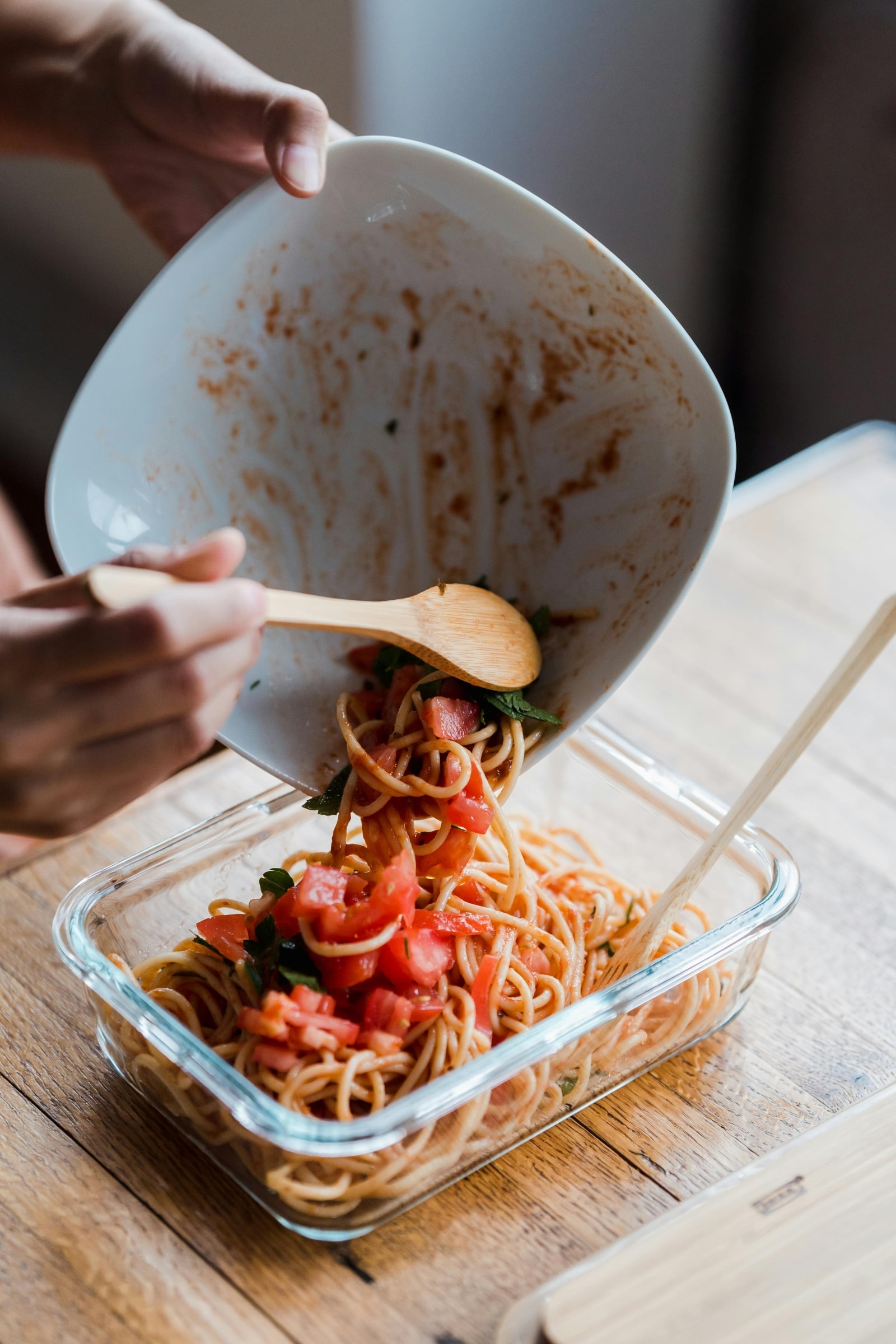 A person stirring spaghetti into a bowl, showcasing the process of preparing a delicious meal.