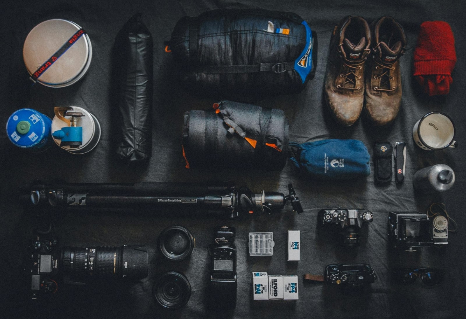 A camera bag's contents displayed on a black surface, showcasing various photography equipment and accessories.