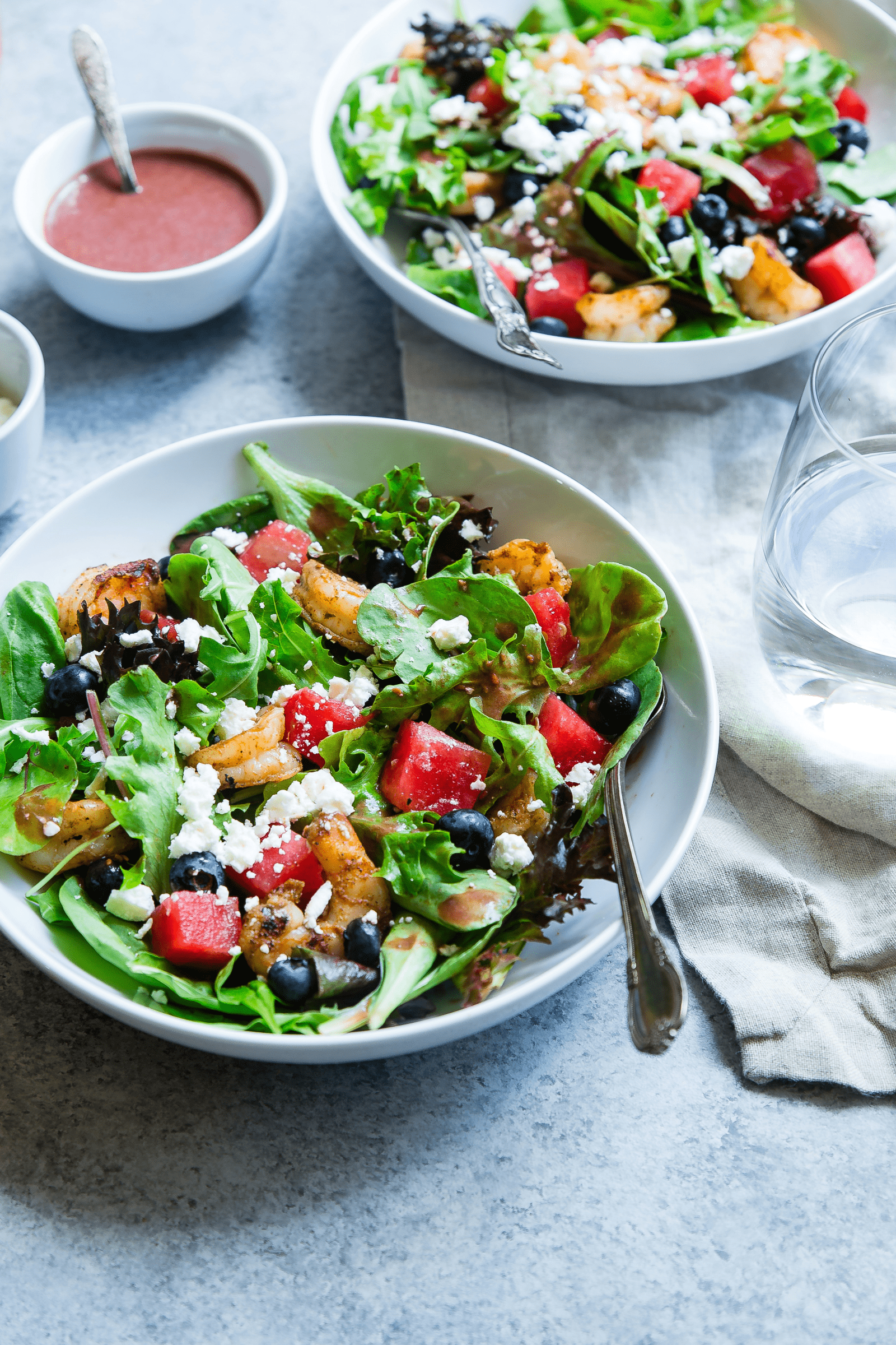 A vibrant salad featuring watermelon, feta cheese, and fresh tomatoes on a white plate.