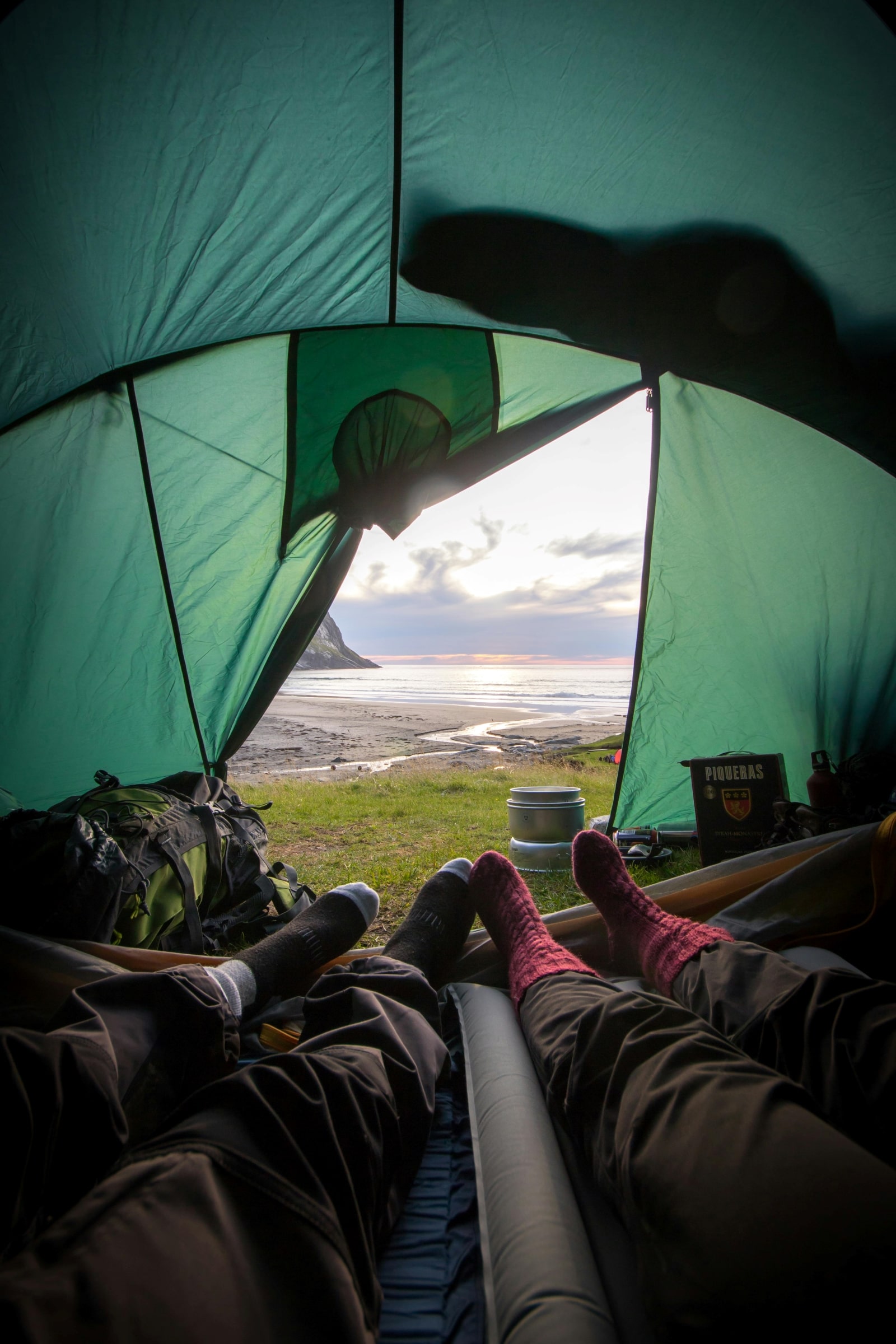 Two individuals relax in a tent, comfortably seated with their feet elevated, enjoying their time together.