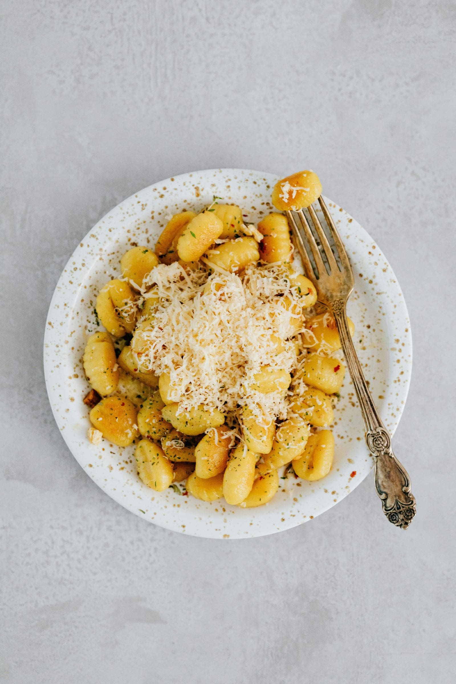 A plate of pasta topped with melted cheese and grated parmesan, elegantly presented for a delightful dining experience.