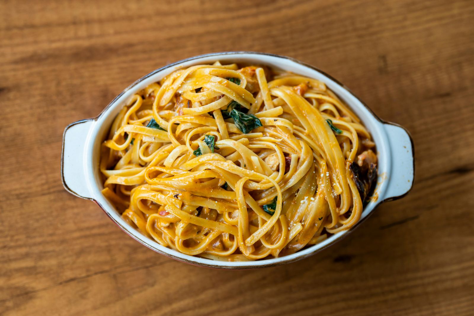 A bowl of spaghetti topped with cheese and fresh herbs, showcasing a delicious Italian dish ready to be enjoyed.