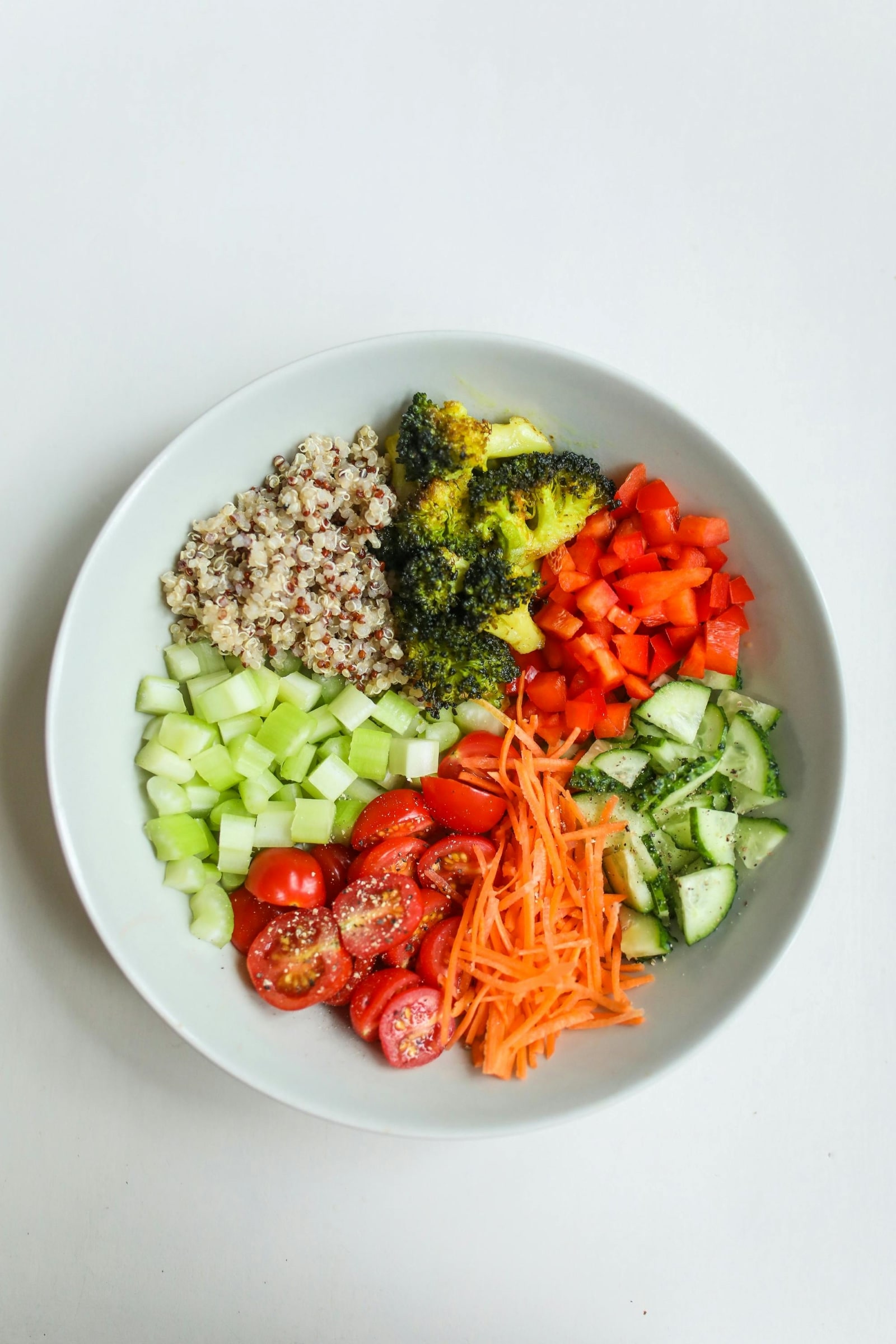 A bowl filled with fresh vegetables, including vibrant broccoli, orange carrots, and red tomatoes, arranged attractively.