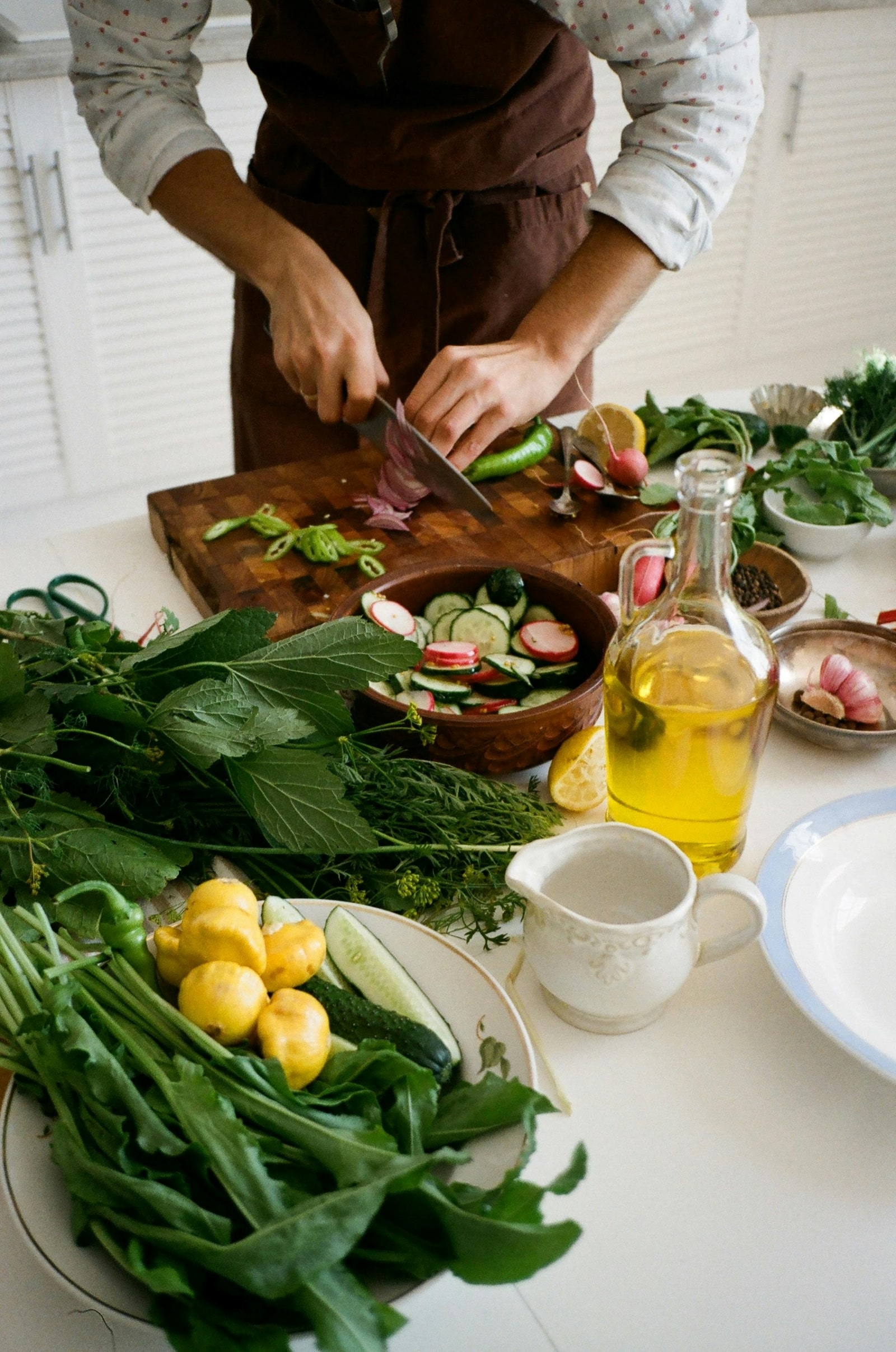 A man skillfully chops fresh vegetables on a wooden table, preparing for a meal.