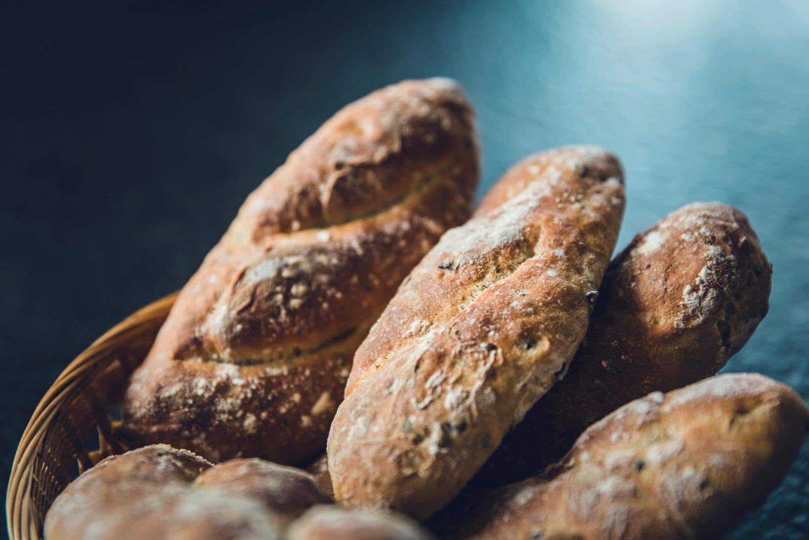 A basket filled with freshly baked bread placed on a wooden table, inviting and warm in appearance.