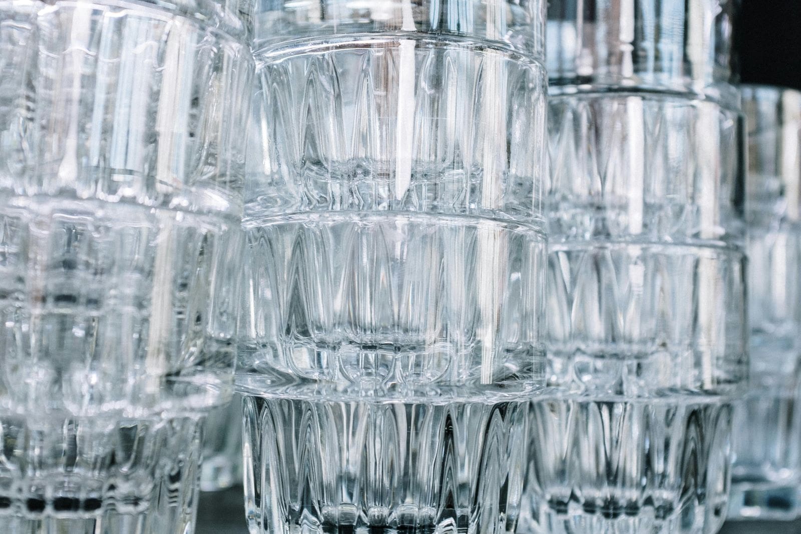 A row of clear glasses arranged neatly on a table, reflecting light and showcasing their transparent design.