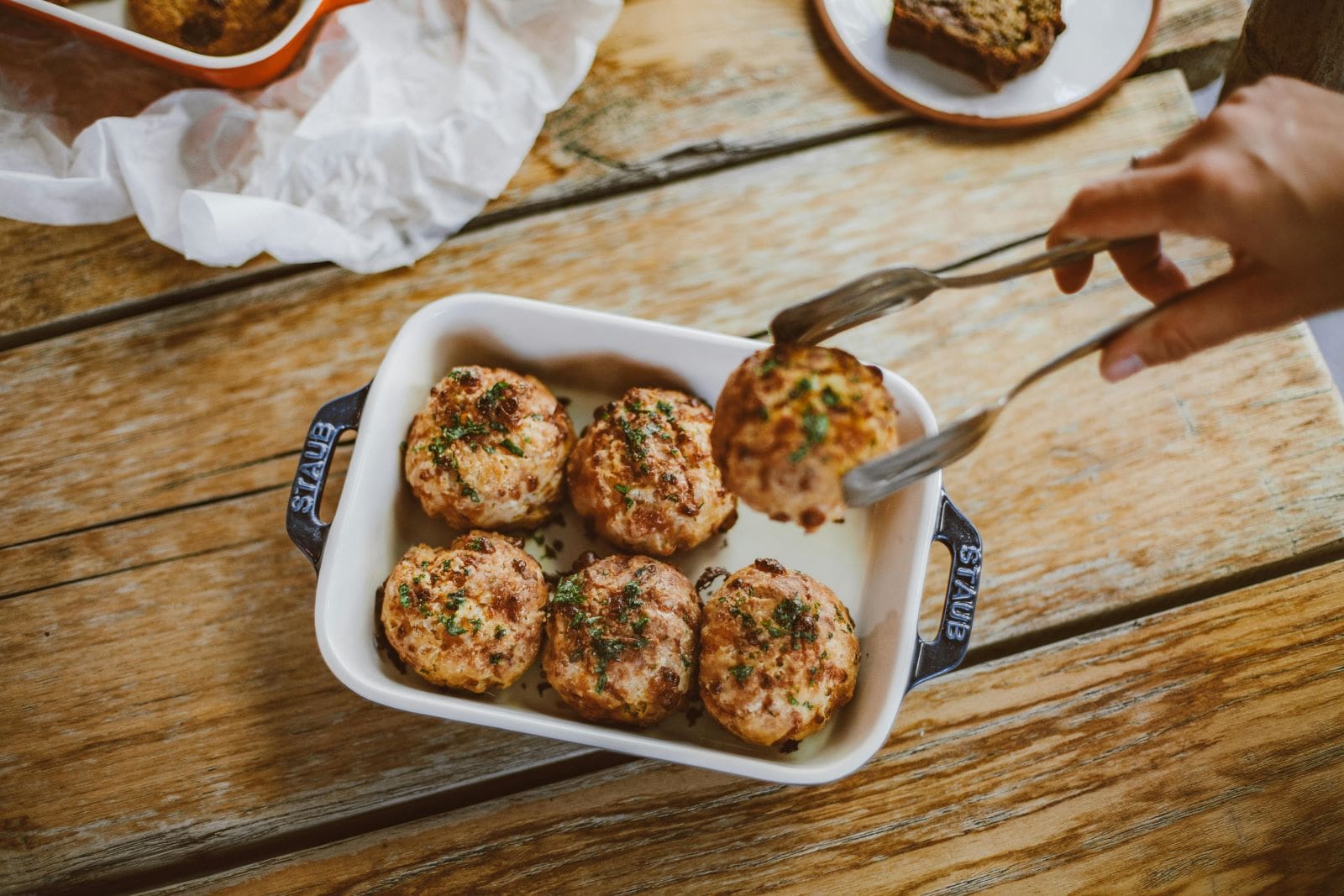 A person holds a fork above a plate of meatballs, ready to enjoy a delicious meal.