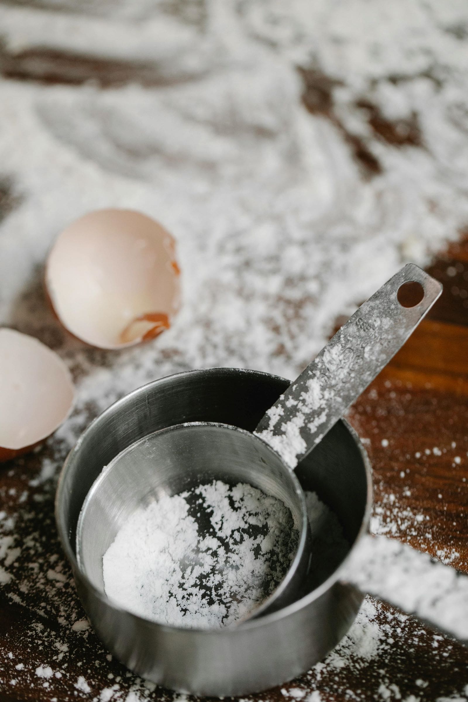 A measuring cup filled with flour placed on a wooden table, ready for baking preparations.