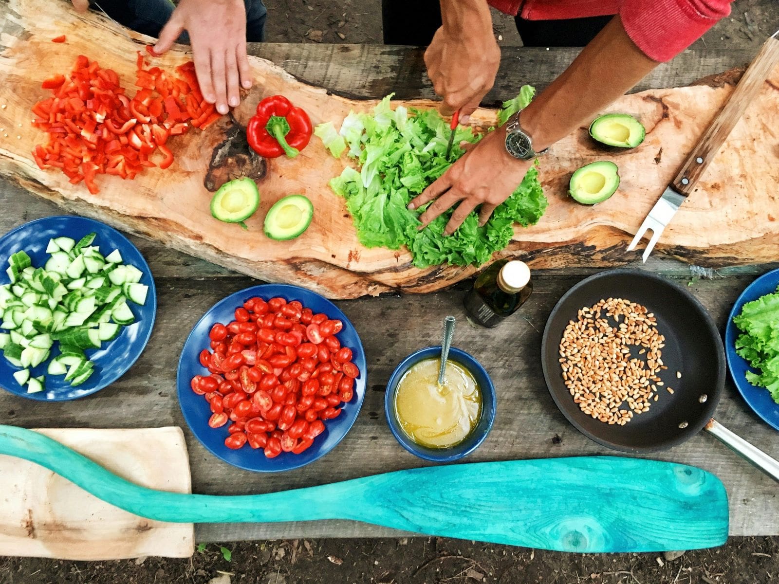 A diverse group of individuals collaborates at a table, skillfully preparing various dishes together.