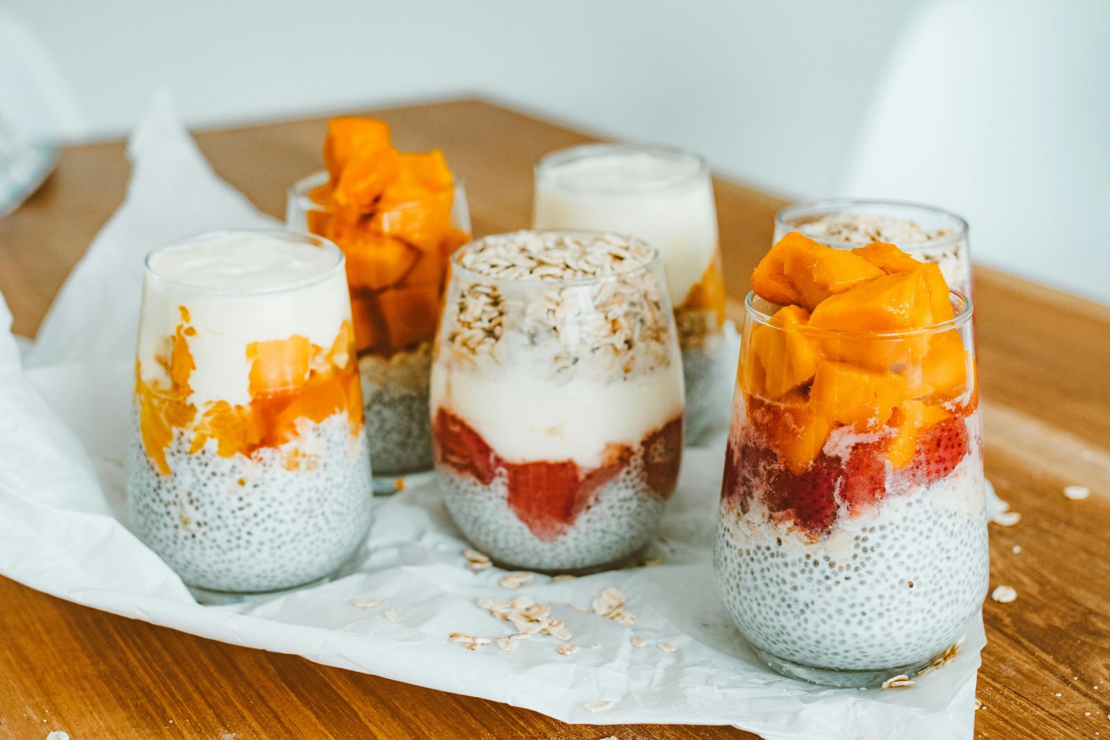 Five glasses of chia pudding topped with various fruits, showcasing a colorful and healthy dessert option.