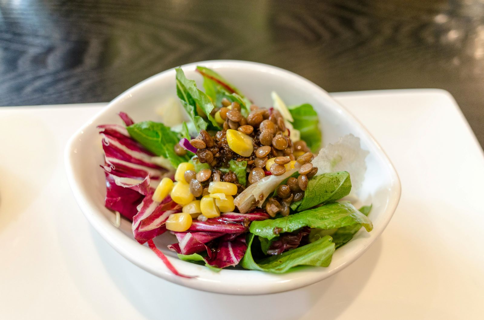 A vibrant bowl of salad featuring fresh greens, sweet corn, and hearty beans, showcasing a colorful and nutritious meal.