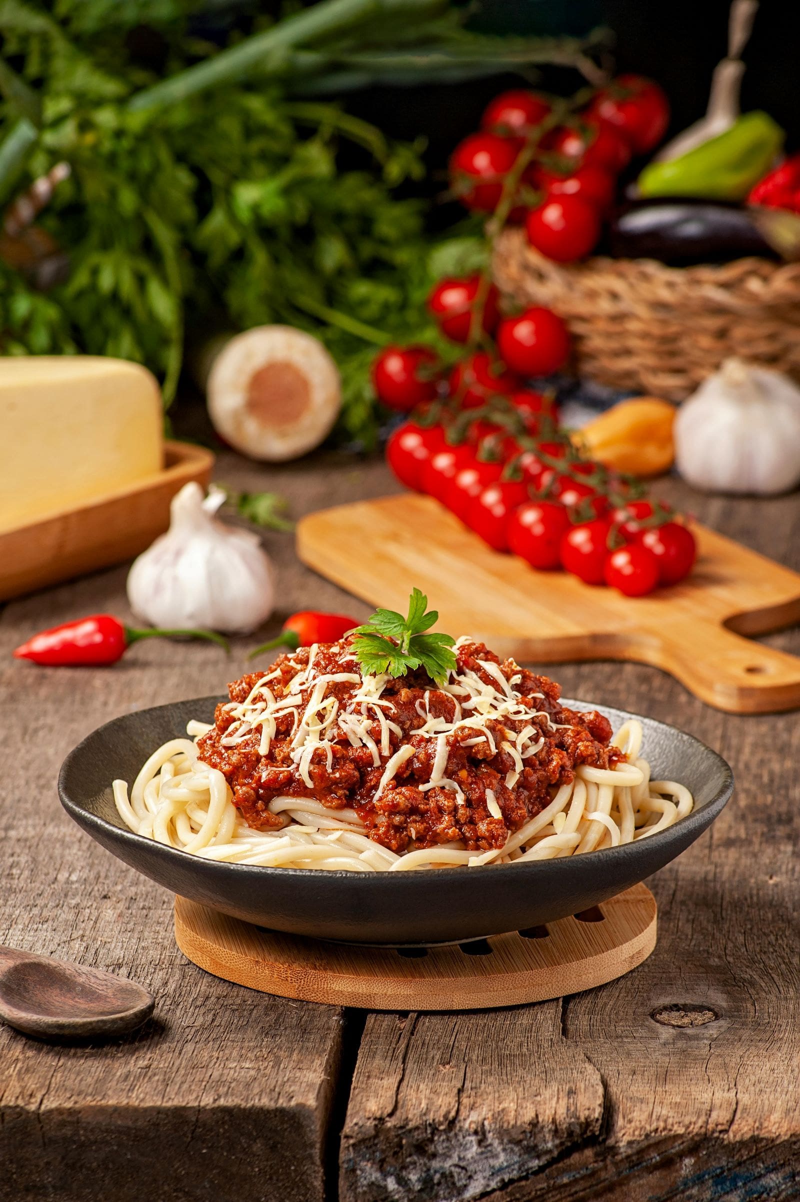 A plate of spaghetti topped with meat sauce and vegetables, elegantly presented on a rustic wooden table.