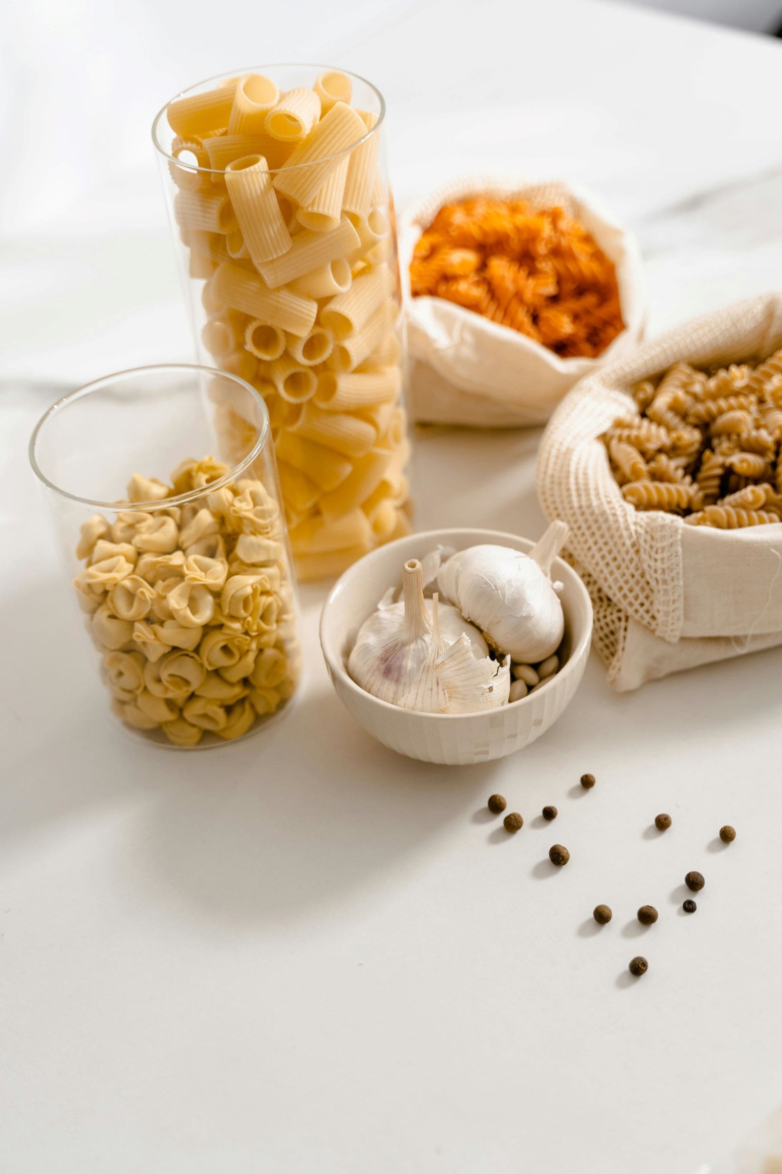 A table displaying a bowl of pasta, garlic, cheese, and nuts, arranged neatly for a delightful meal presentation.