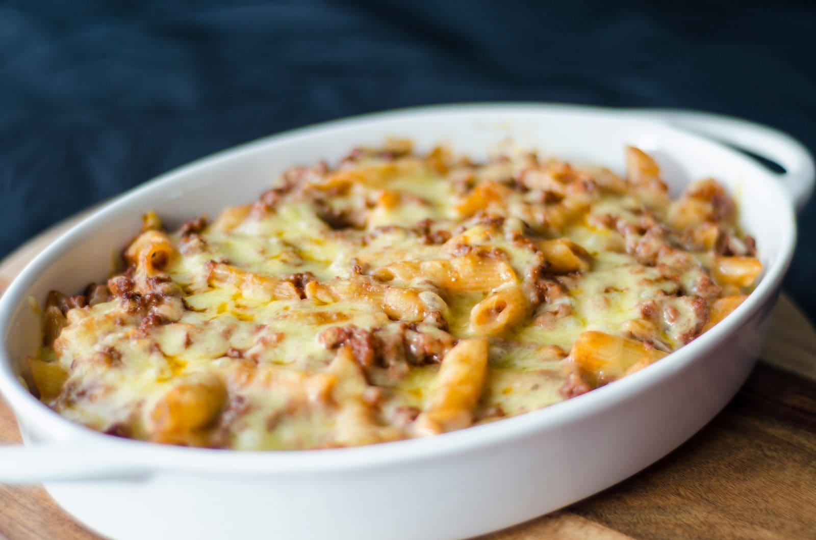 A creamy cheesy pasta bake served in a white dish, showcasing a golden, bubbly top and rich, comforting texture.