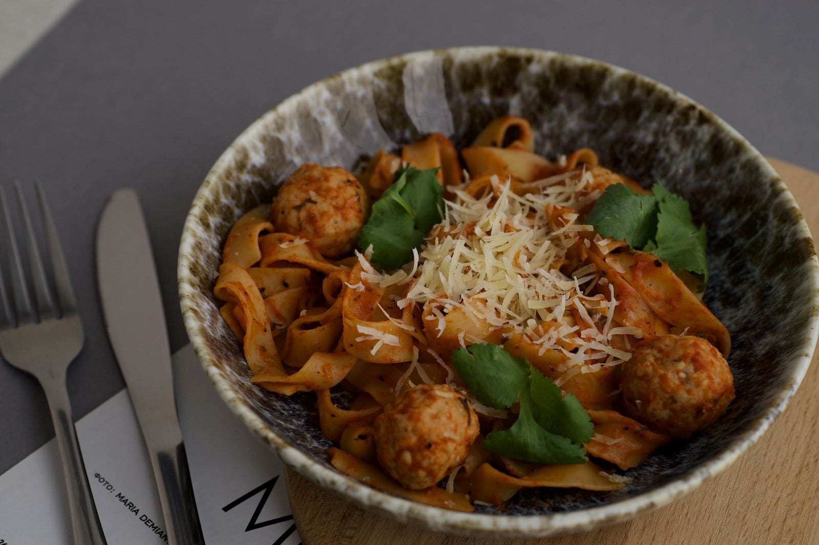 A bowl of pasta topped with meatballs and sprinkled with cheese, showcasing a delicious Italian dish.